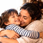 Single mother hugging her smiling child on a sofa at home